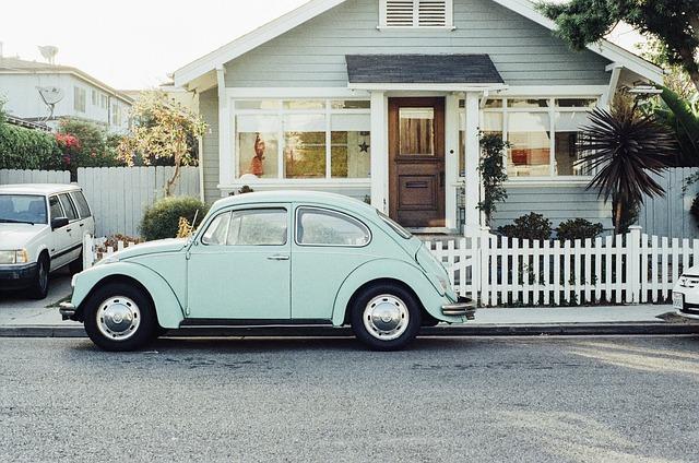 VW Beetle Car in pale green in front of a pitched roof house painted in the same colour